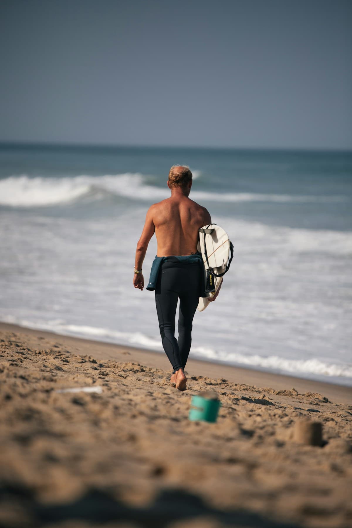 A surfer standing on the beach watching incoming waves, studying the ocean before paddling out
