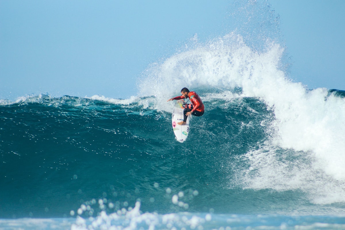 A surfer riding down the face of a clean wave at sunset