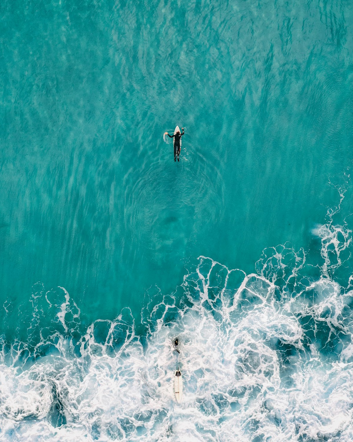 A surfer committing to a steep late drop on a sizeable overhead wave